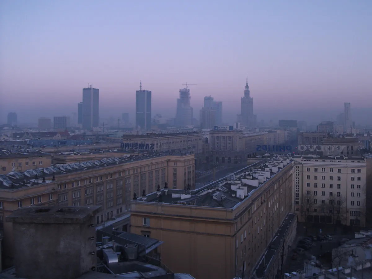 Warsaw skyline in violet haze with the Palace of Culture and Science rising above winter rooftops